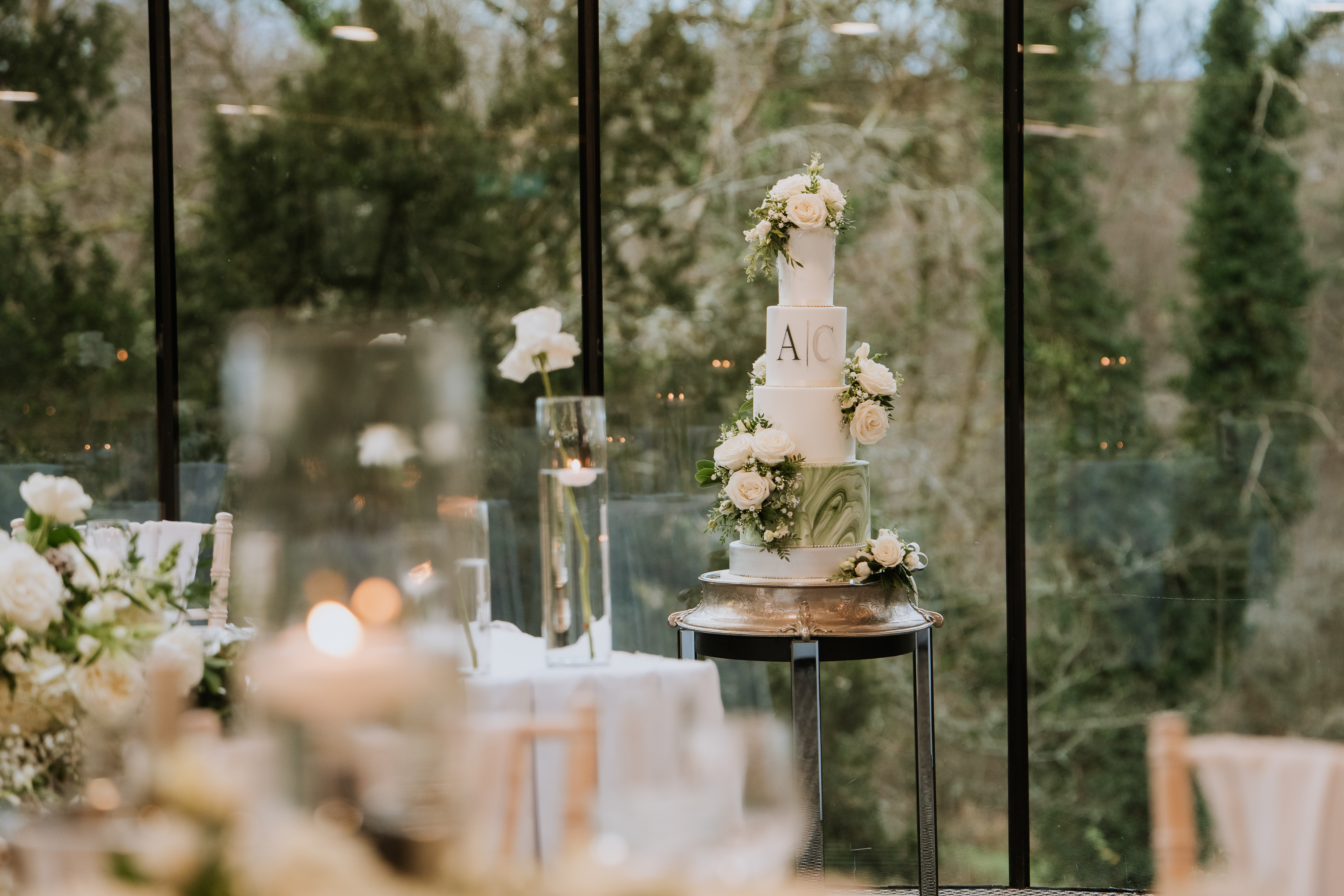 Luxury floral wedding cake displayed beside floor-to-ceiling windows