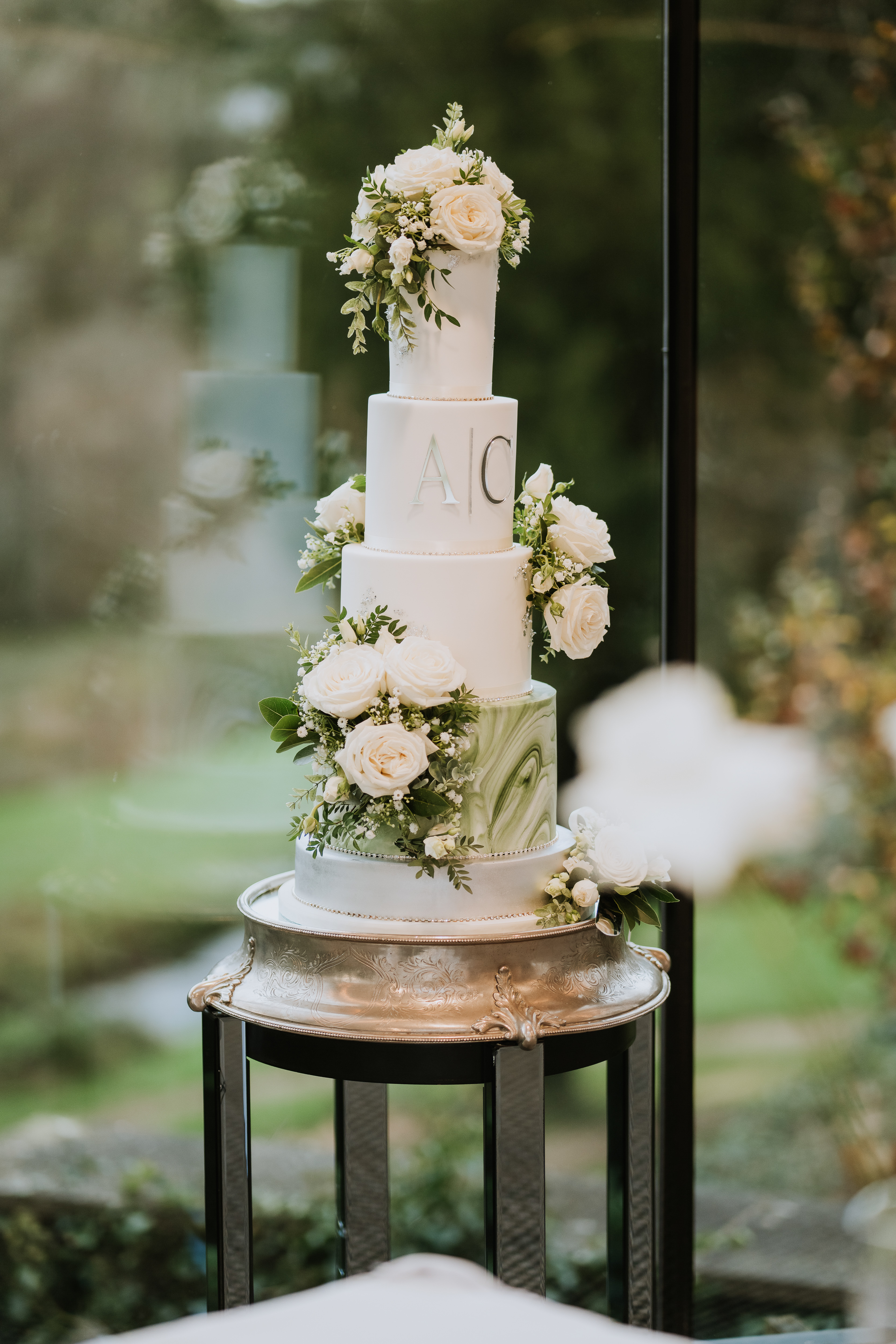 Luxury floral wedding cake displayed beside floor-to-ceiling windows